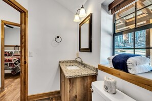Ein Badezimmer mit einem Holzlagerflächen, einem Waschbecken, einem Spiegel und einem Fenster mit Blick auf eine verschneite Landschaft.