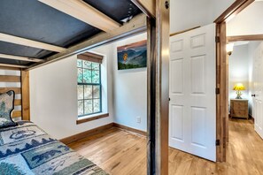 Ein Schlafzimmer mit einem Bett, einem Fenster, einer Tür und einem an der Wand hängenden Bild.