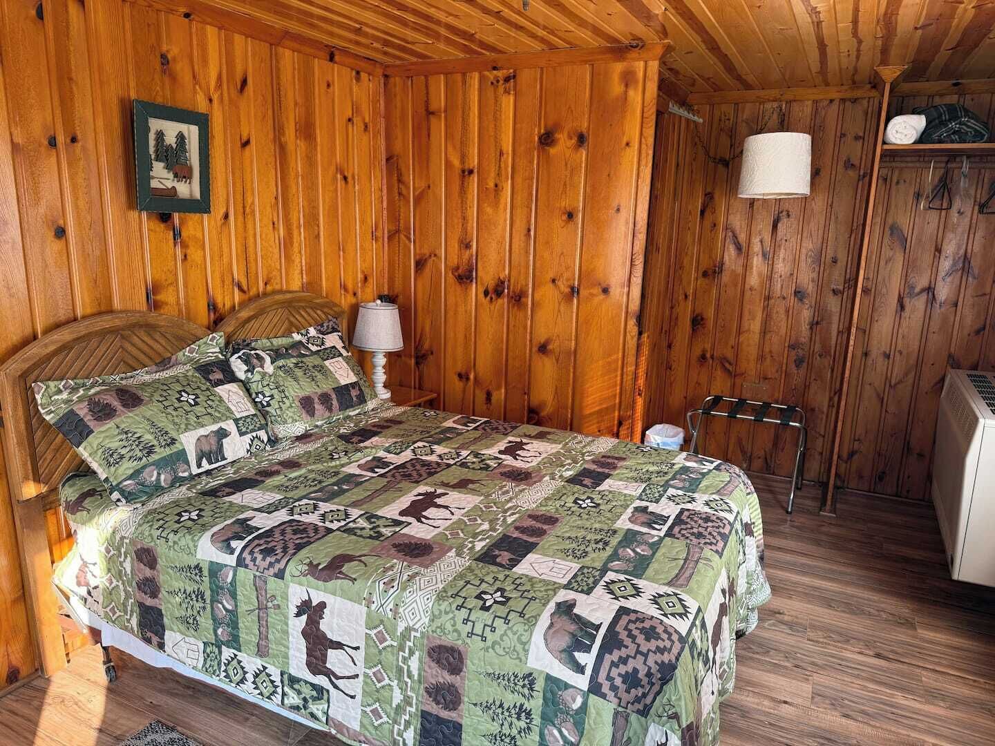 Une pièce en bois comprenant un lit, une table de chevet, une lampe et une petite table avec une chaise.