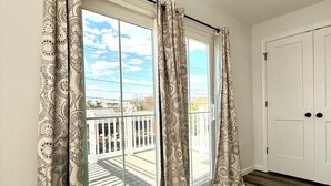 Ein Zimmer mit einer großen Schiebeglas-Tür, die auf einen Balkon mit weißer Brüstung führt.