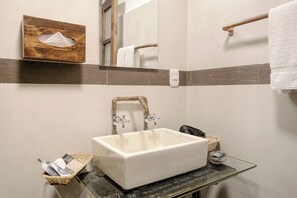 Une salle de bain avec un lavabo blanc, un porte-serviettes en bois et un miroir.