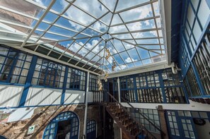 Un atrium couvert avec un plafond de verre, des murs en pierre et un escalier.