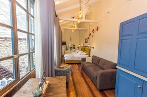 Une pièce comprenant un lit, un canapé, une armoire bleue et une fenêtre avec des rideaux.