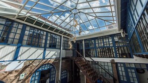 Een overdekte atrium met glazen dak, stenen muren en een trap.