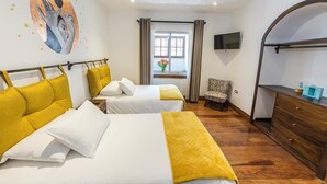 Habitación de hotel con dos camas, televisión, cómoda y ventana con cortinas.