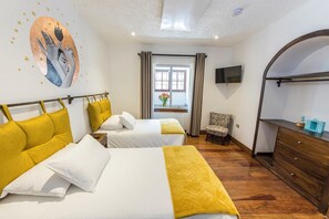 Une chambre d’hôtel avec deux lits, une télévision, une commode et une fenêtre avec des rideaux.
