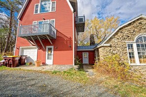 A two-story house with a red exterior, a stone chimney, and a small porch.