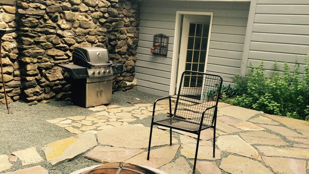 A stone patio with a fire pit, a grill, and a chair. - Charming Red Tower, Loft  ambiance, Mountain views, AC, WiFi, Berkshires NY (Petersburgh)