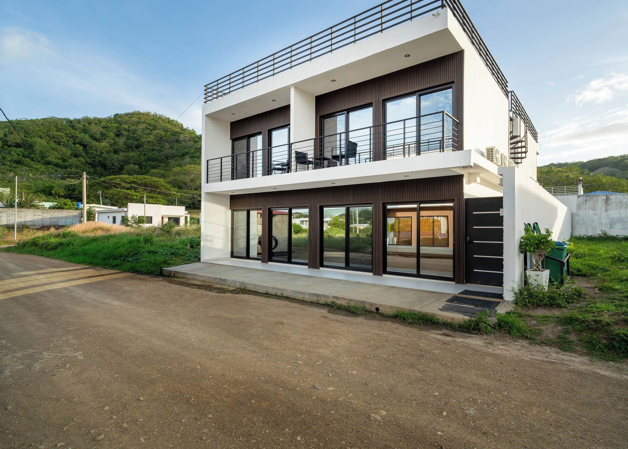 A modern two-story building with a balcony, large windows, and a paved entrance.