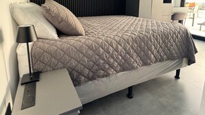 Ett modernt sovrum med en säng, ett sängbord och inbyggda hyllor.