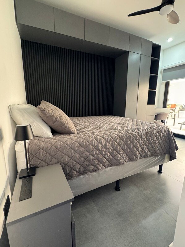 A modern bedroom with a bed, bedside table, and built-in shelving.