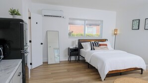 Un dormitorio con cama, mesita de noche y ventana.