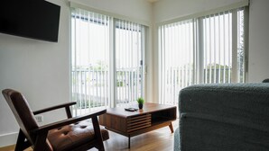 Una sala moderna con una mesa de centro de madera, un sofá de cuero y un televisor montado en la pared.