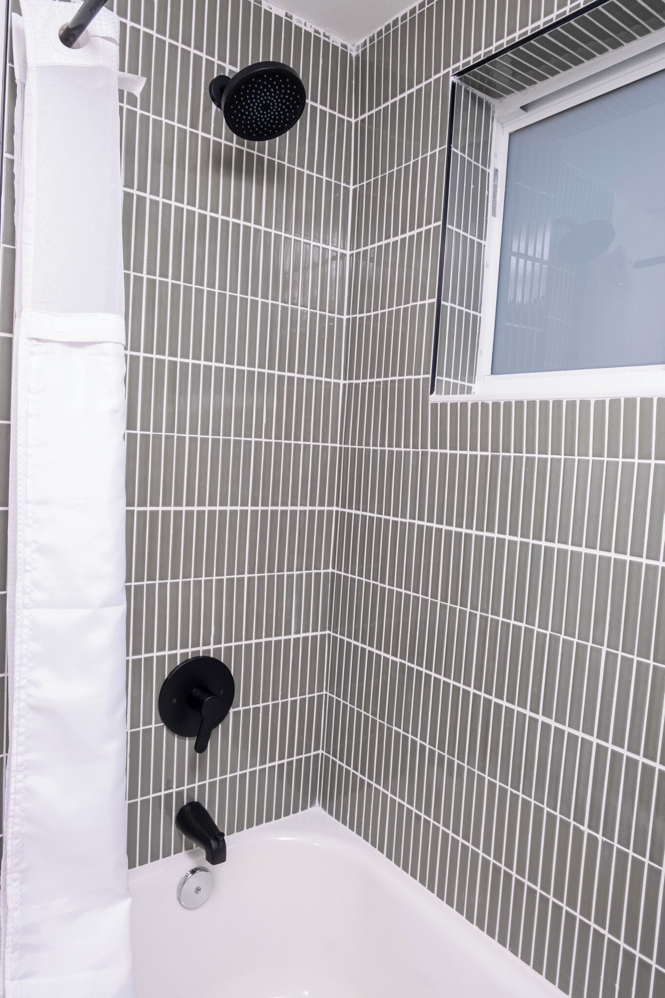 A bathroom with a shower, a bathtub, and a window.