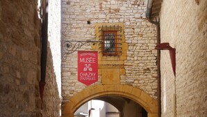 A narrow cobblestone alleyway with stone walls and an arched entrance. A sign for the Musée Chazay d'Azergues is visible. - Cosy studio in the heart of the village of Chazay (Chazay-d'Azergues)