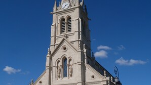 A large church with a tall steeple, a clock, and a large arched entrance. - Cosy studio in the heart of the village of Chazay (Chazay-d'Azergues)