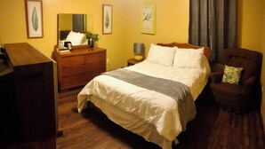 Ein Schlafzimmer mit Bett, Kommode, Stuhl und Schreibtisch.