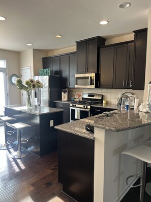 A modern kitchen with dark cabinetry, a stainless steel microwave, a gas stove, and granite countertops.