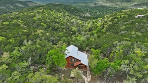 A cabin in a forested area with a view of distant hills.