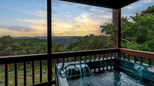 A hot tub with a view of a forest and mountains.