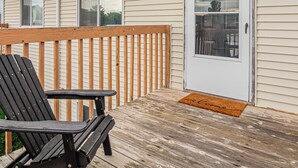 A wooden deck with a black chair, a white door with a window, and a welcome mat. - 10 min to Sanford I Smart TV I Queen I Free Prking (Fargo)