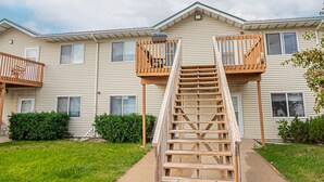 A residential building with a central wooden staircase leading to a balcony. - 10 min to Sanford I Smart TV I Queen I Free Prking (Fargo)