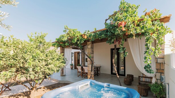 Een hottub, buitenmeubilair en een pergola met klimop.