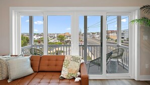 A balcony with a sofa, chairs, and a view of a cityscape.