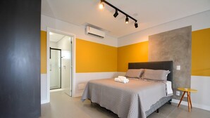A modern bedroom with a bed, a small table, and an air conditioning unit. - Sunset Lagoa (Florianopolis)