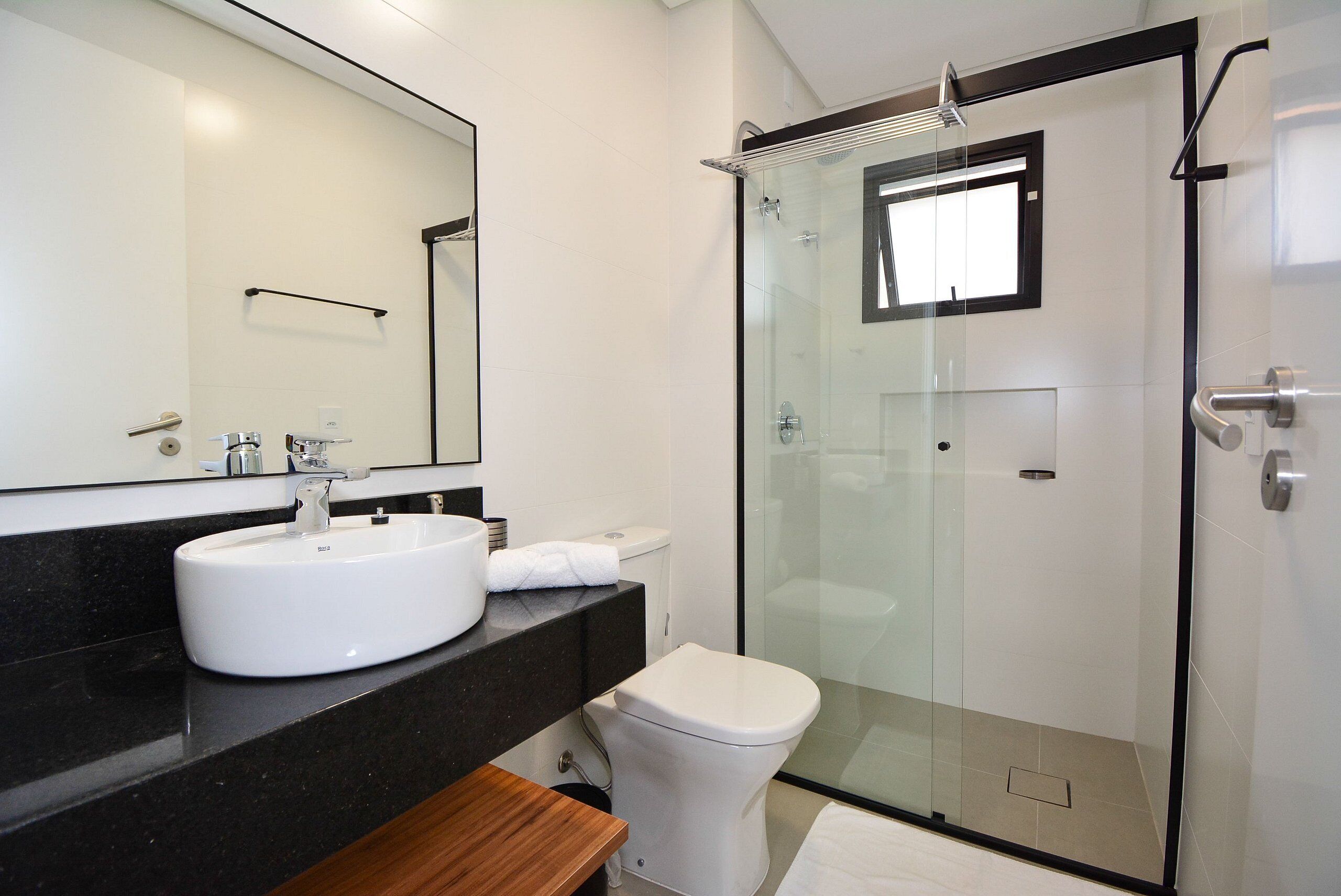 A modern bathroom with a white sink, a toilet, and a glass-enclosed shower.
