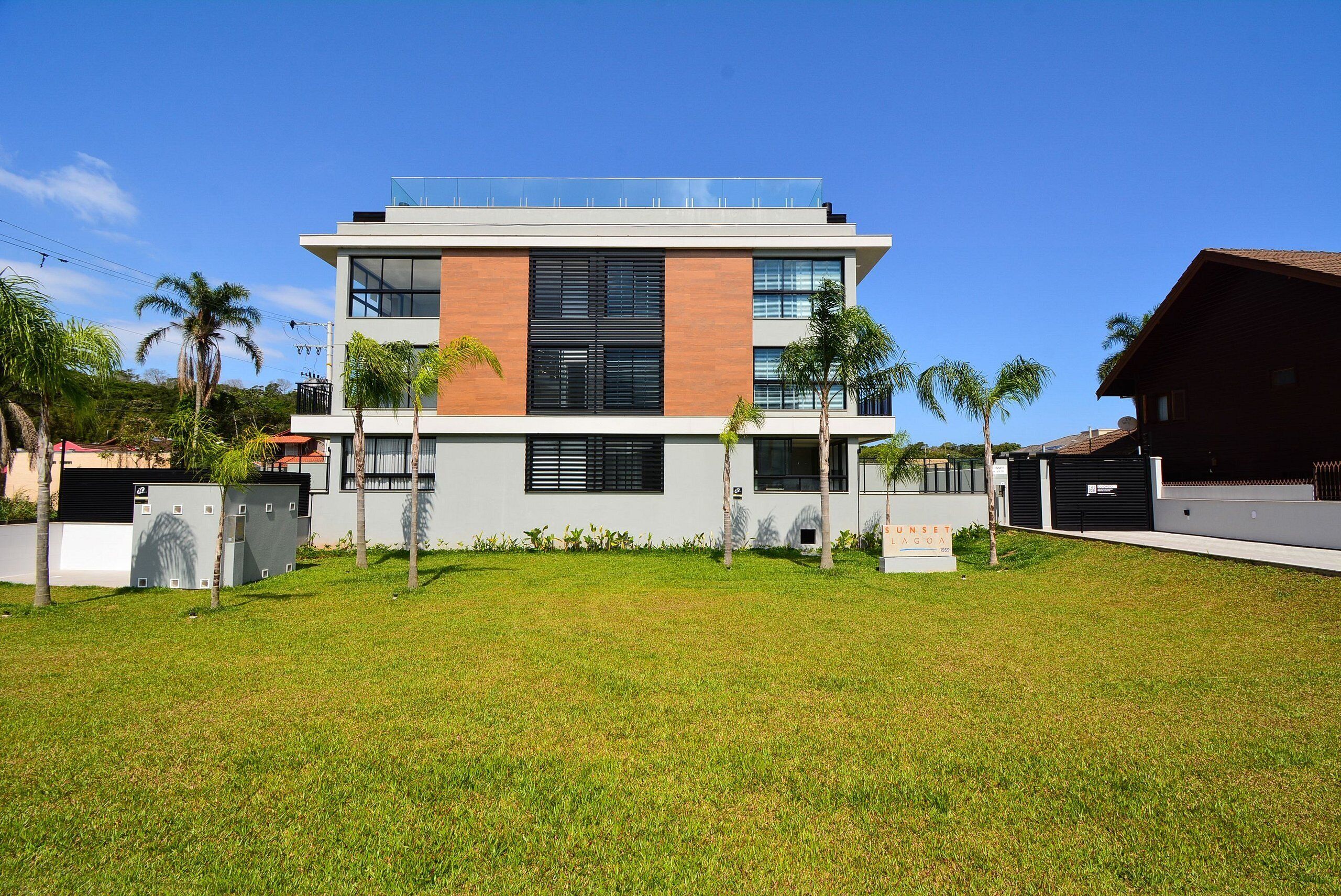 Un bâtiment moderne à deux étages, doté d’un toit plat, de grandes fenêtres et d’une enseigne indiquant « Sunset Villa ».