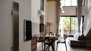 A modern kitchen with a built-in digital lock, a dining area with a table and chairs, and a living area with a sofa and a balcony with a view. - Sunset Lagoa (Florianopolis)