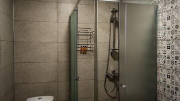 Une salle de bain dotée d’une douche à parois de verre, de toilettes et d’un mur carrelé orné d’un motif décoratif.