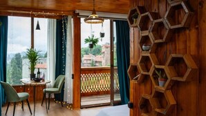 A wooden room with a bed, a table with chairs, a colorful rug, and a balcony with plants. - Greenland Pheria - Cabin near Batumi (Batumi)