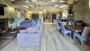 A spacious living area with a large sofa, dining table, and kitchen in the background.