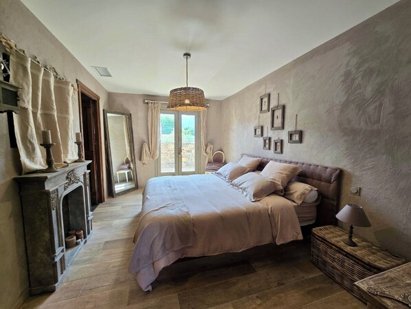 Un dormitorio con una cama grande, una chimenea, un espejo y vistas al exterior.