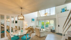 A spacious living area with a glass dining table, wicker chairs, a sofa, and a staircase. - Beachfront Condo w/ Balcony on Manasota Key (Englewood)