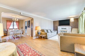 Ein geräumiges Wohnzimmer mit Kamin, einem Essbereich mit Tisch und Stühlen und einer gemütlichen Sitzecke mit Sofa und Sesseln.