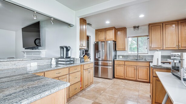 A modern kitchen with granite countertops, stainless steel appliances, wooden cabinets, and a large island. - 8 Mi to Dtwn: Home w/ Fireplace & Games in LA! (Los Angeles)