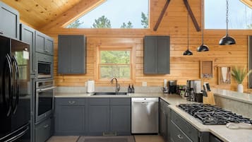Una cucina moderna con mobili antracite, elettrodomestici in acciaio inossidabile e un'ampia finestra.