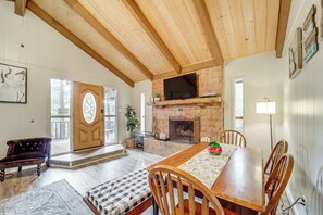 A spacious living room with a wooden ceiling, a fireplace, a dining table, and a comfortable seating area. - Near Fossil Creek & Trails: Scenic Pine Cabin! (Pine)