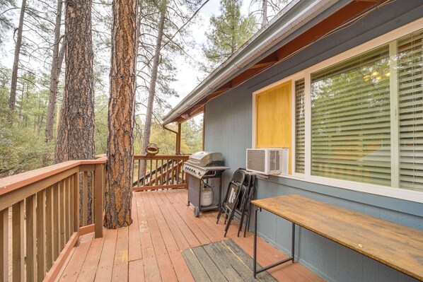 A deck with a grill and outdoor seating, surrounded by tall trees. - Near Fossil Creek & Trails: Scenic Pine Cabin! (Pine)