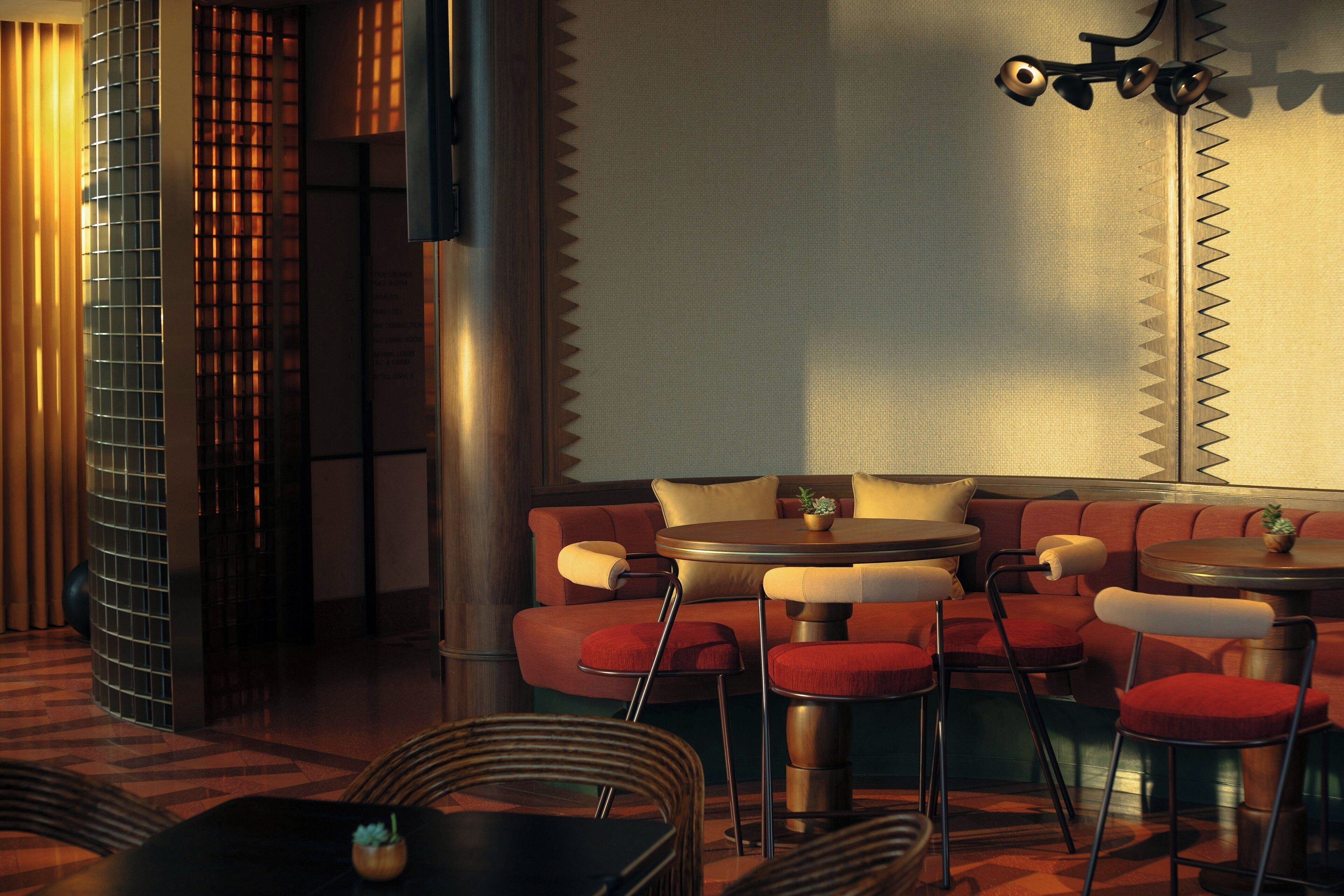 A modern interior with a seating area featuring red upholstered chairs and a round table.