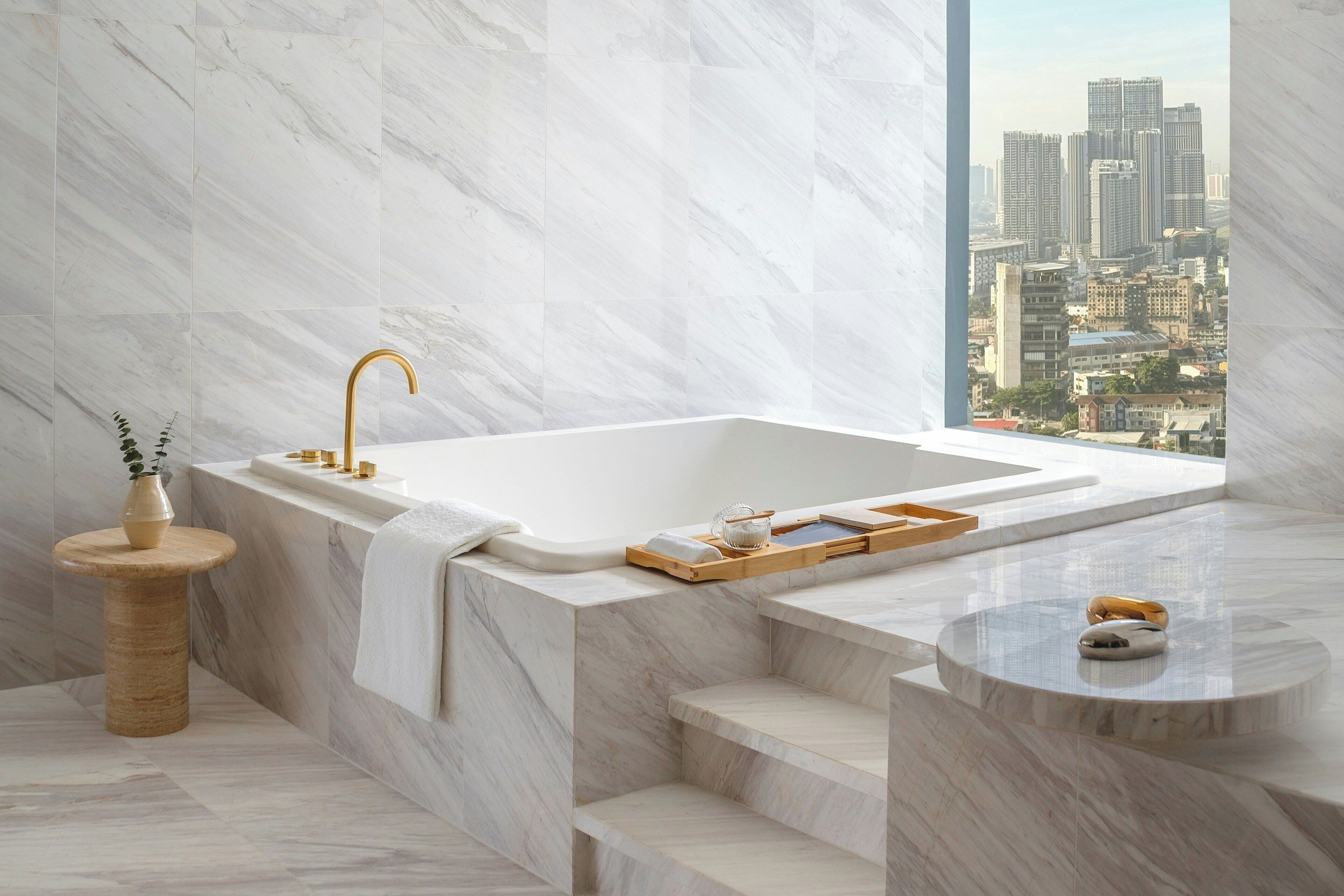 Une salle de bain moderne avec un lavabo en marbre, une baignoire et une vue sur la ville.