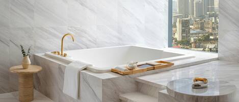 Une salle de bain moderne avec un lavabo en marbre, une baignoire et une vue sur la ville.