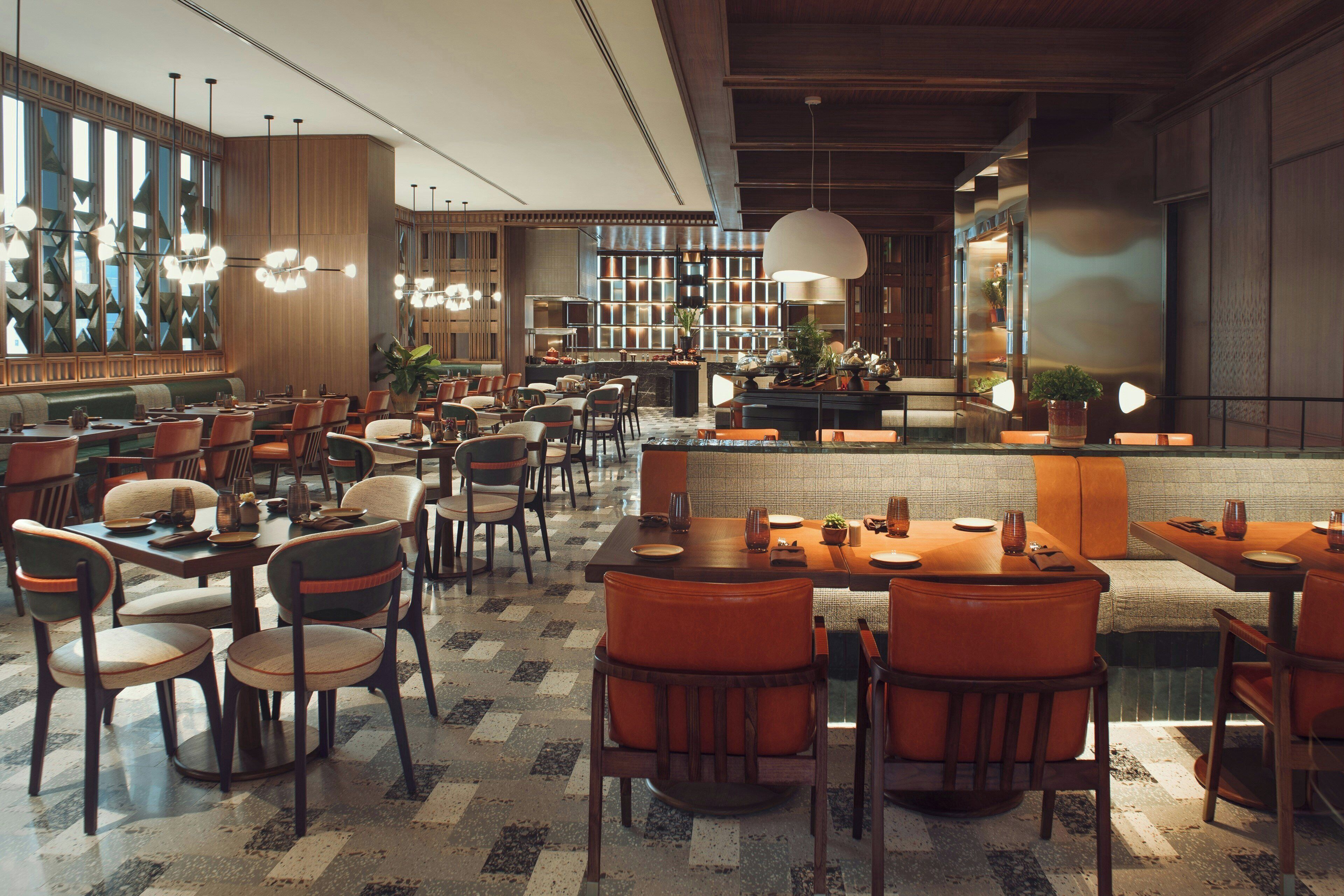 Un restaurante espacioso con varias mesas y sillas, una zona de bar y una cocina al fondo.