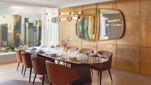 A modern dining room with a panoramic city view, a large round table, and contemporary chairs.