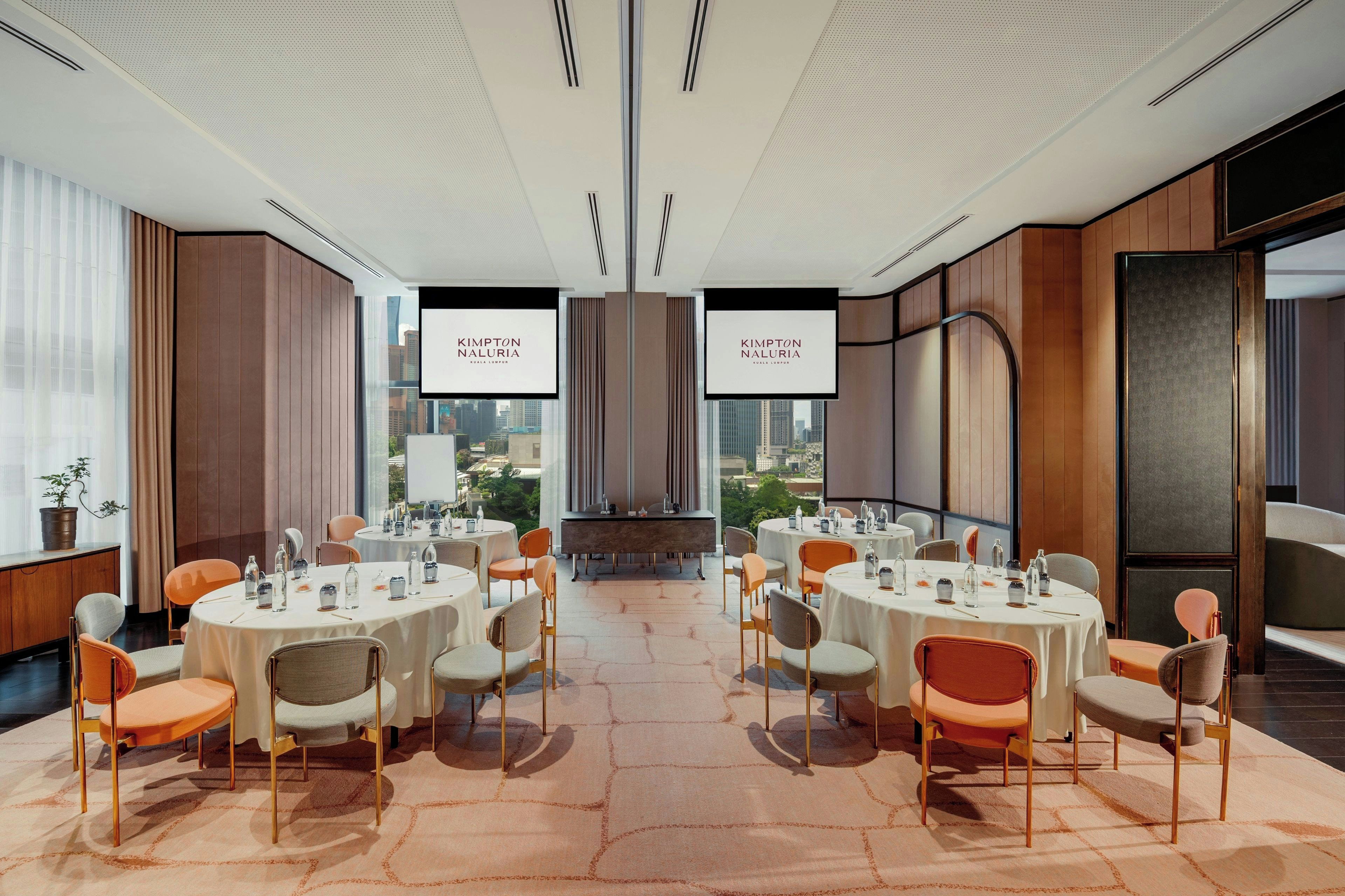 A conference room with round tables, chairs, and a city view.