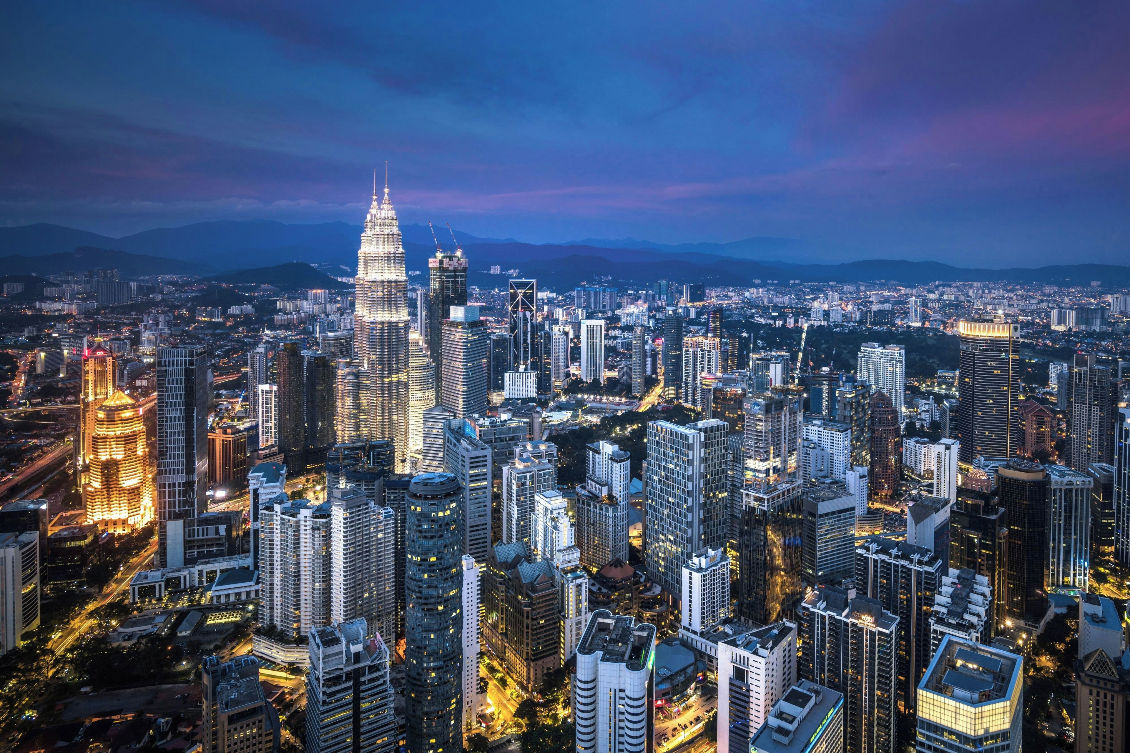 A cityscape with a prominent skyscraper, dense urban buildings, and a network of roads.