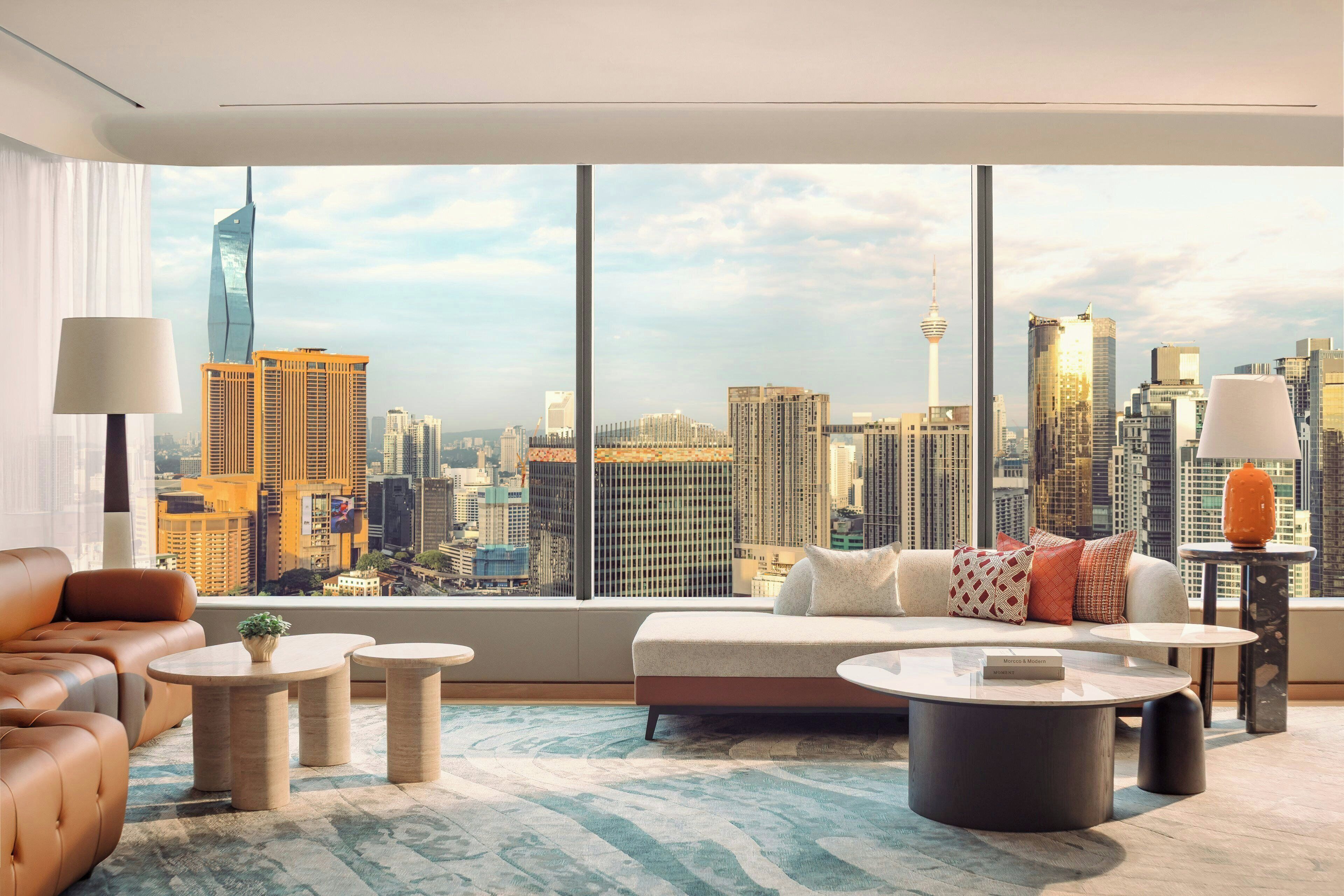 A modern living room with a city view, featuring a sofa, coffee table, and lamp.